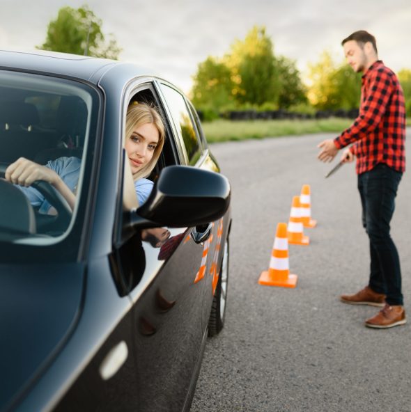 Instructor is happy with the driving of his female student between cones, lesson in driving school. Man teaching lady. Driver's license education